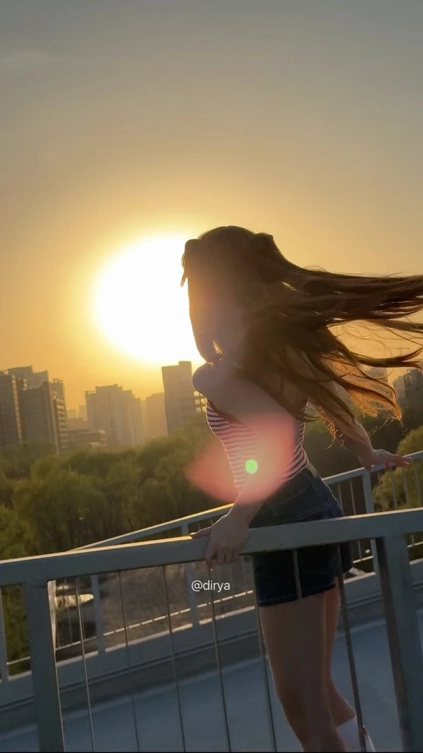 一位长发、红色和白色衬衫的女人站在一座桥上。