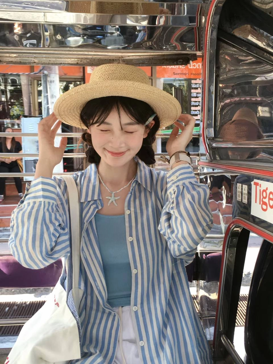 一位穿着泥帽和蓝色衬衫的女人坐在公交车上。