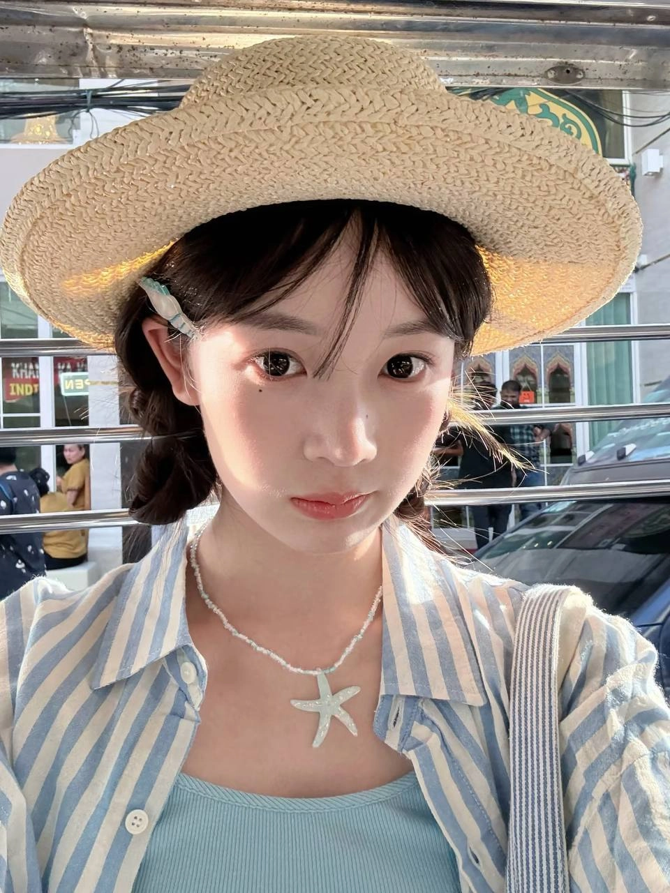 一位穿着泥帽和蓝色衬衫的女人坐在公交车上。