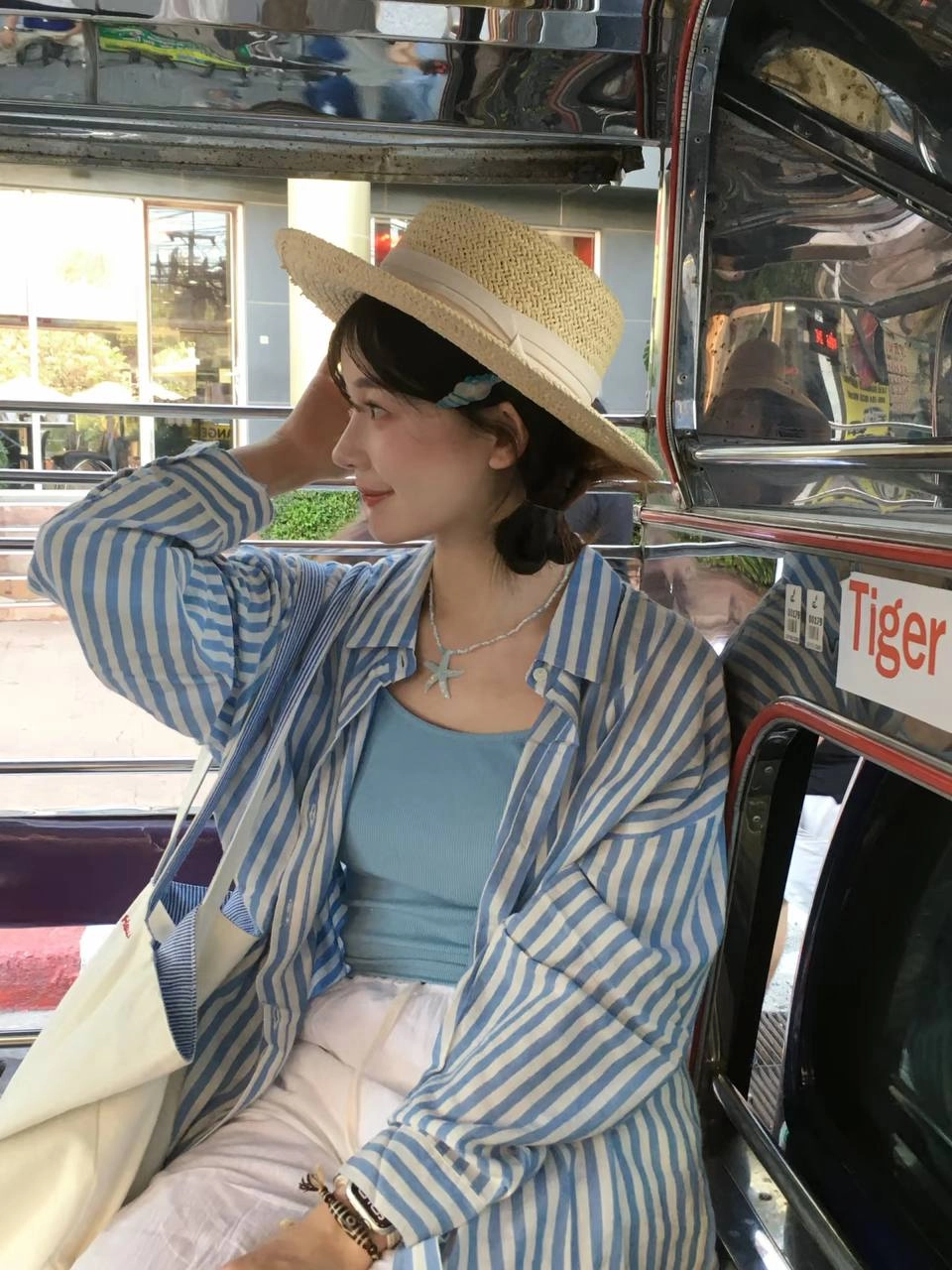 一位穿着泥帽和蓝色衬衫的女人坐在公交车上。