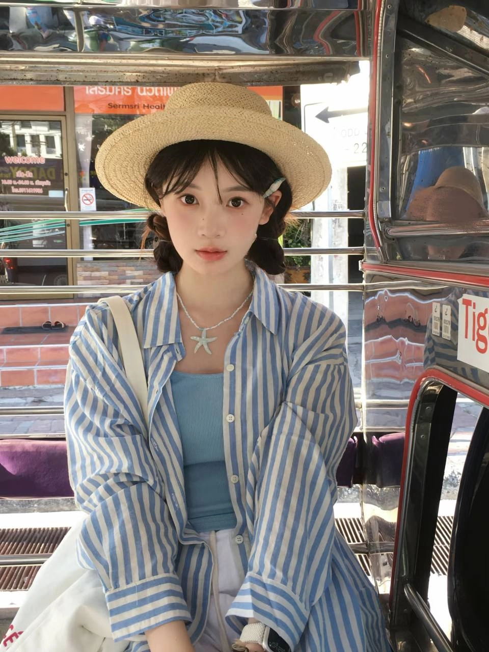 一位穿着泥帽和蓝色衬衫的女人坐在公交车上。