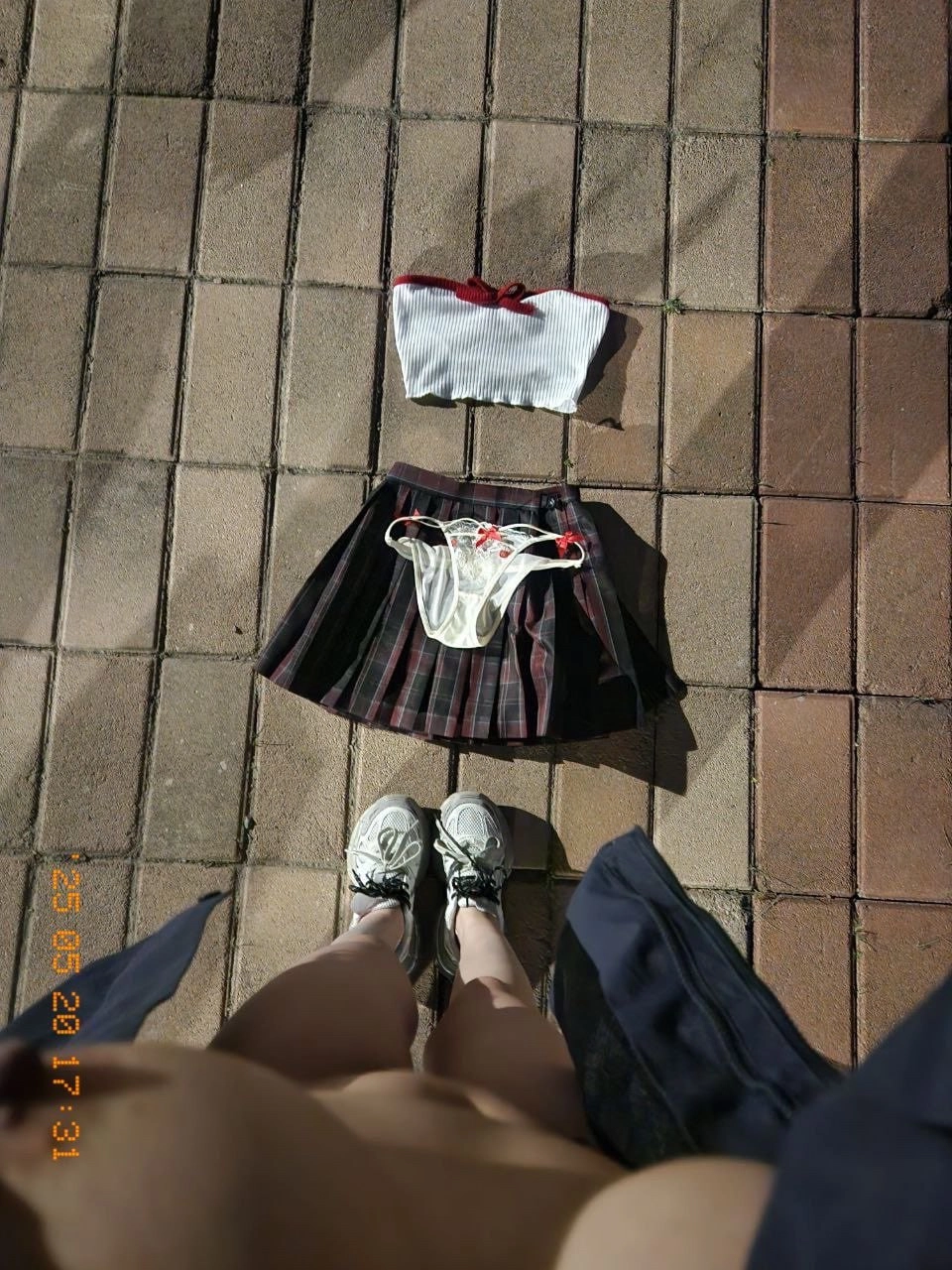 人站在一个砖的走廊上,戴着裙子和胸罩。