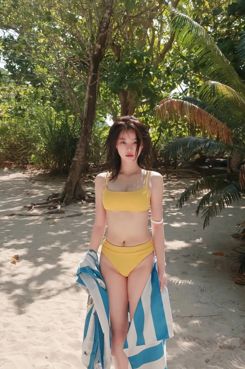 穿着黄色比基尼的女人站在海滩上。