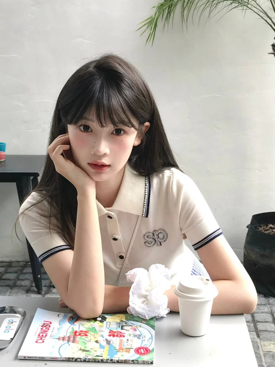 穿着白色衬衫和蓝色条纹的女人坐在一张桌子上。