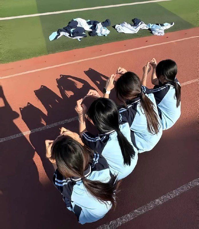 三个女孩坐在轨道上,其中穿着蓝色衬衫。