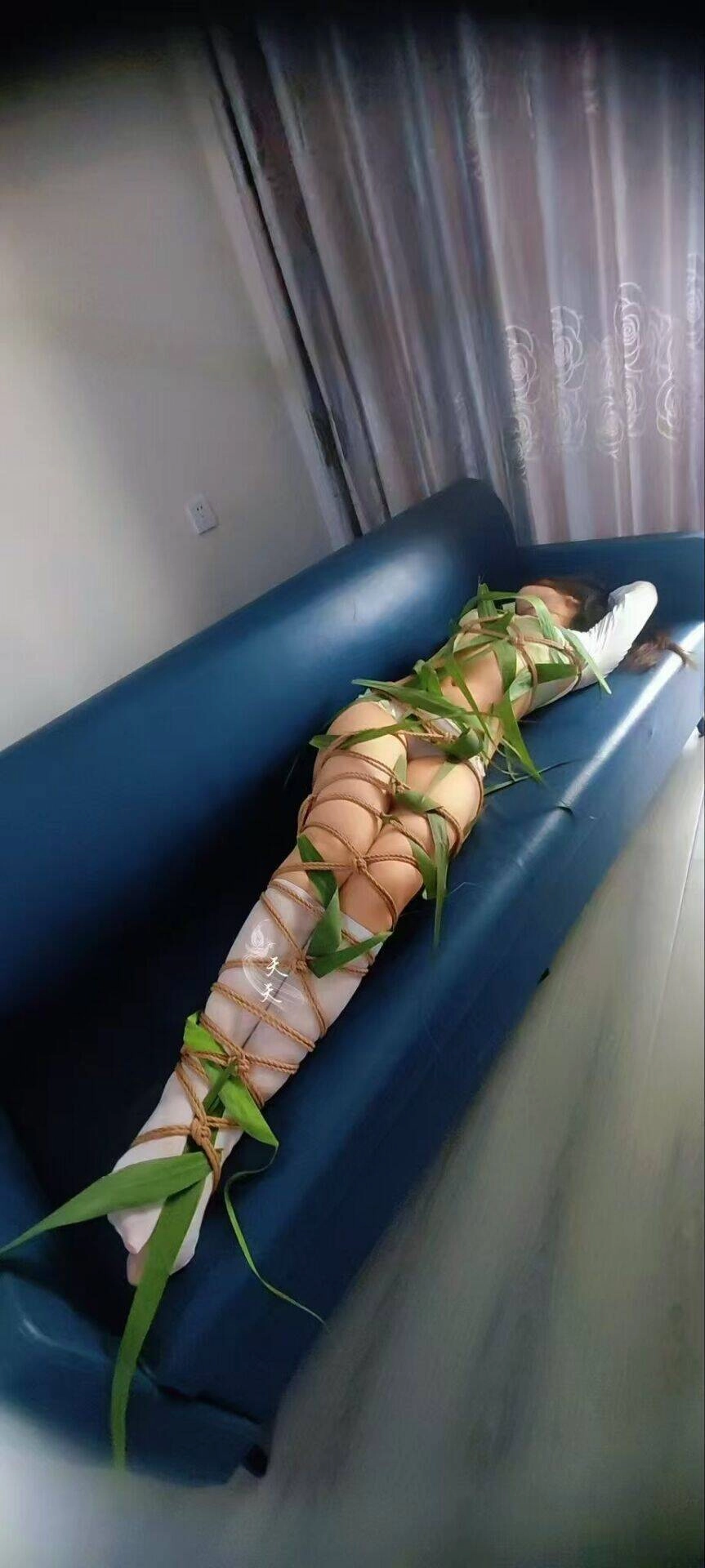 女人被绑在一张带植物叶子的沙发上。