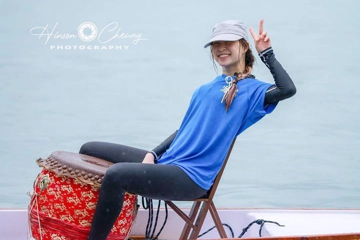 一位穿着蓝色衬衫和帽子的女人坐在椅子上,发出和平的信号。