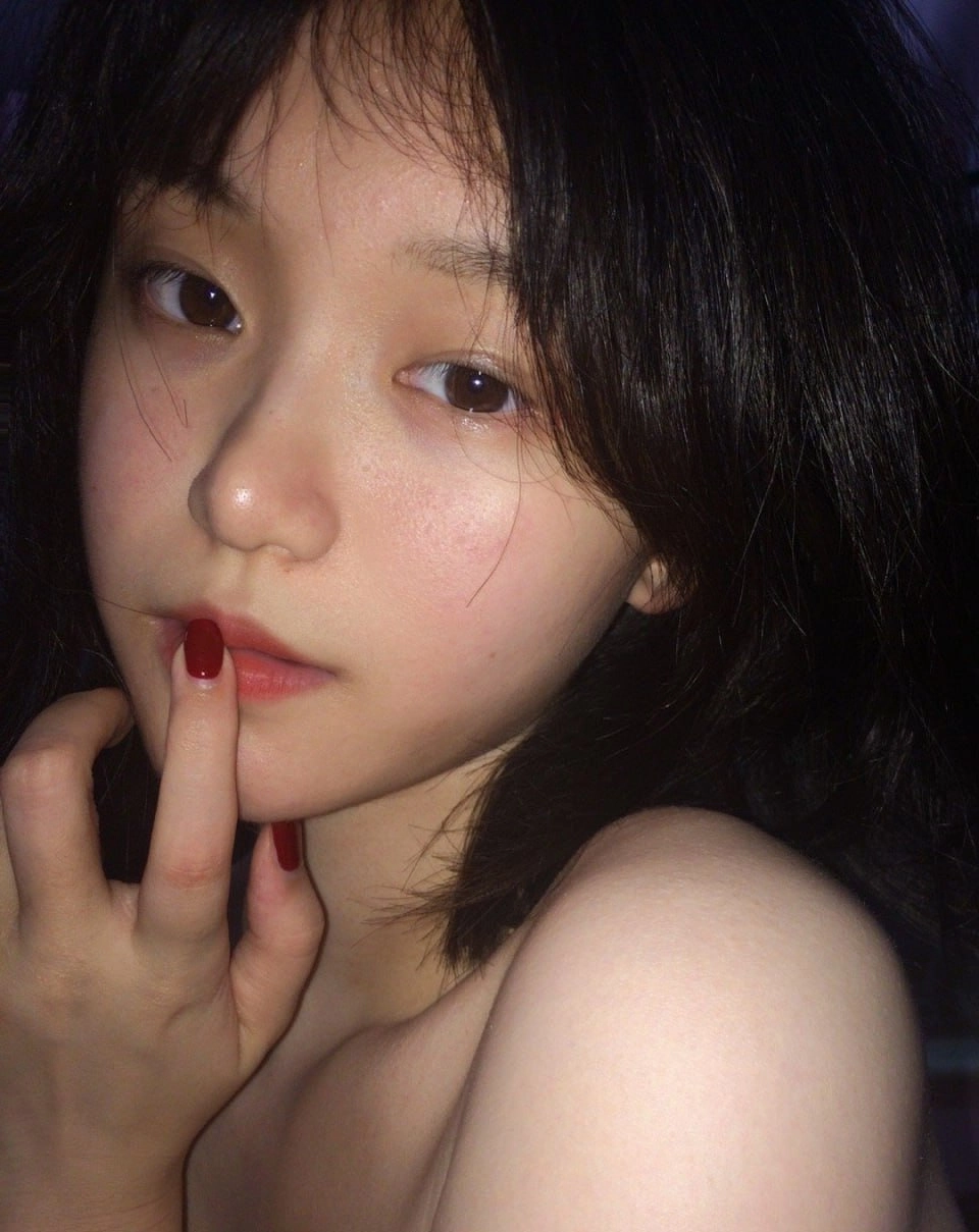 黑头发和红色指甲的女人在她的手指上涂抹。