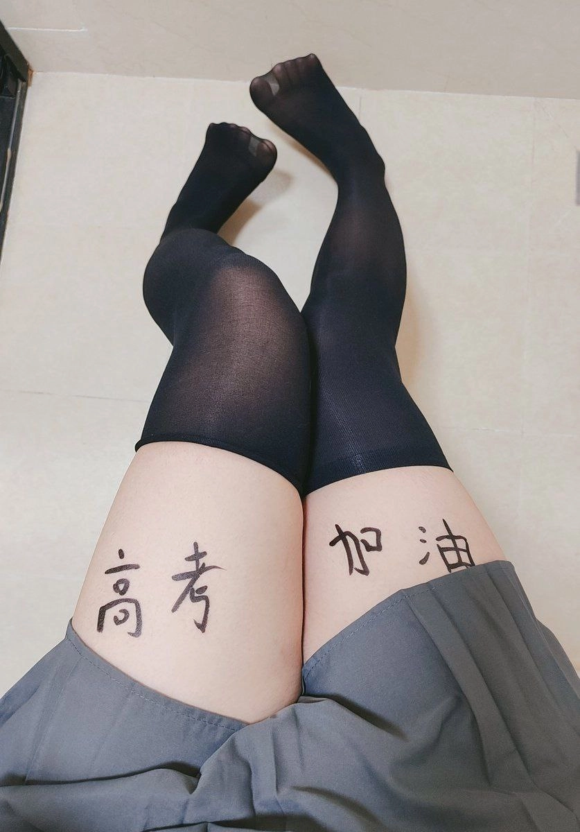 穿着黑色袜子和灰色裙子的女人,她的腿上有中国字符纹身。