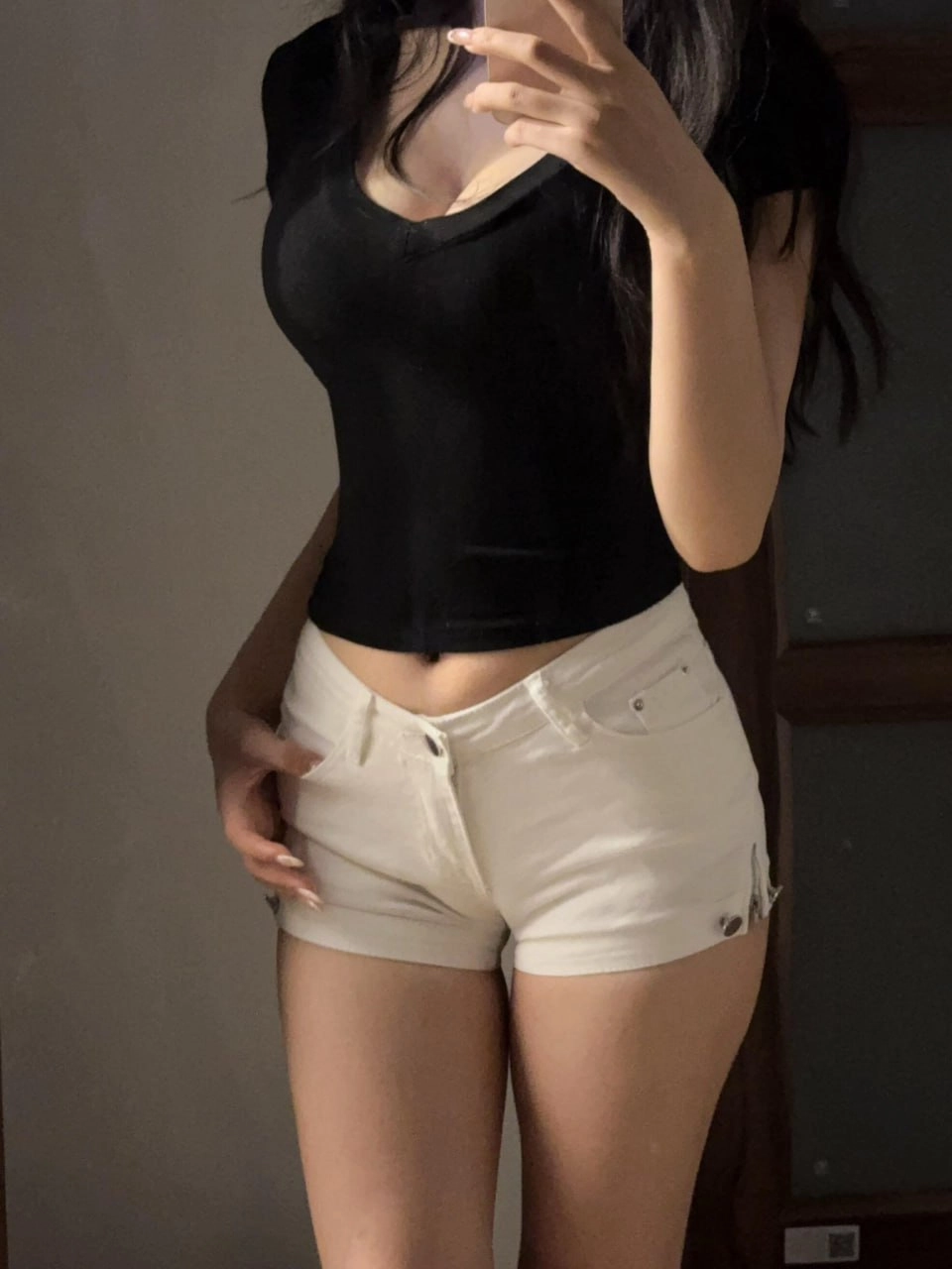 一位穿着黑色衬衫和白色短裤的女人拍了一张自拍。