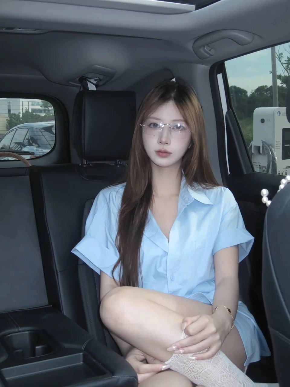 戴着眼镜和蓝色衬衫的女人坐在车里。