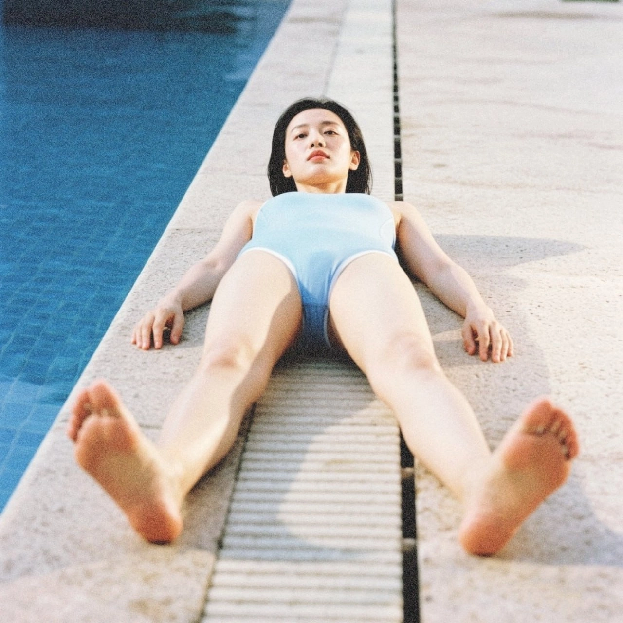 一位穿着蓝色泳衣的女人躺在游泳池的边缘。