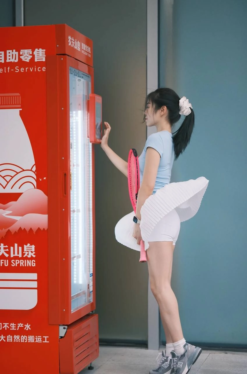 一位穿着白色衣服的女人站在一台售货机前。