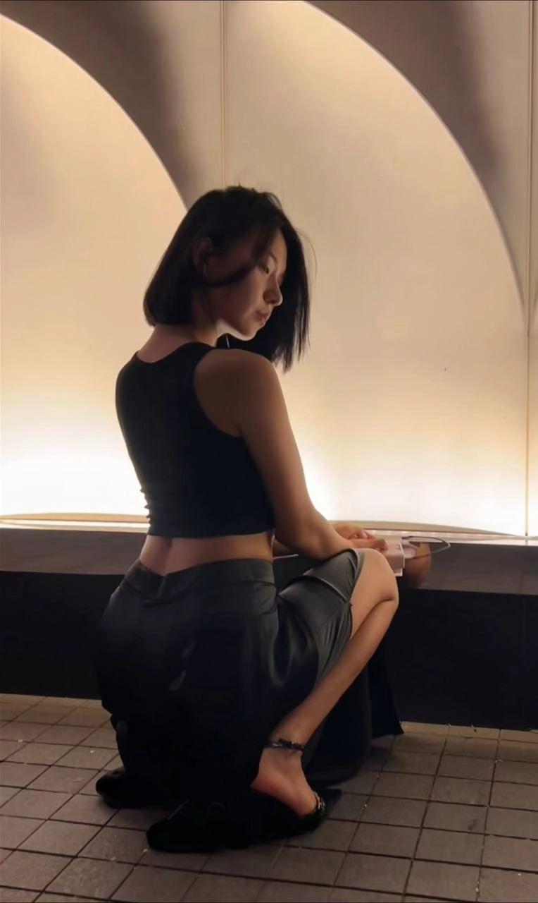 穿着黑色衬衫和黑色裙子的女人坐在一个凳子上。