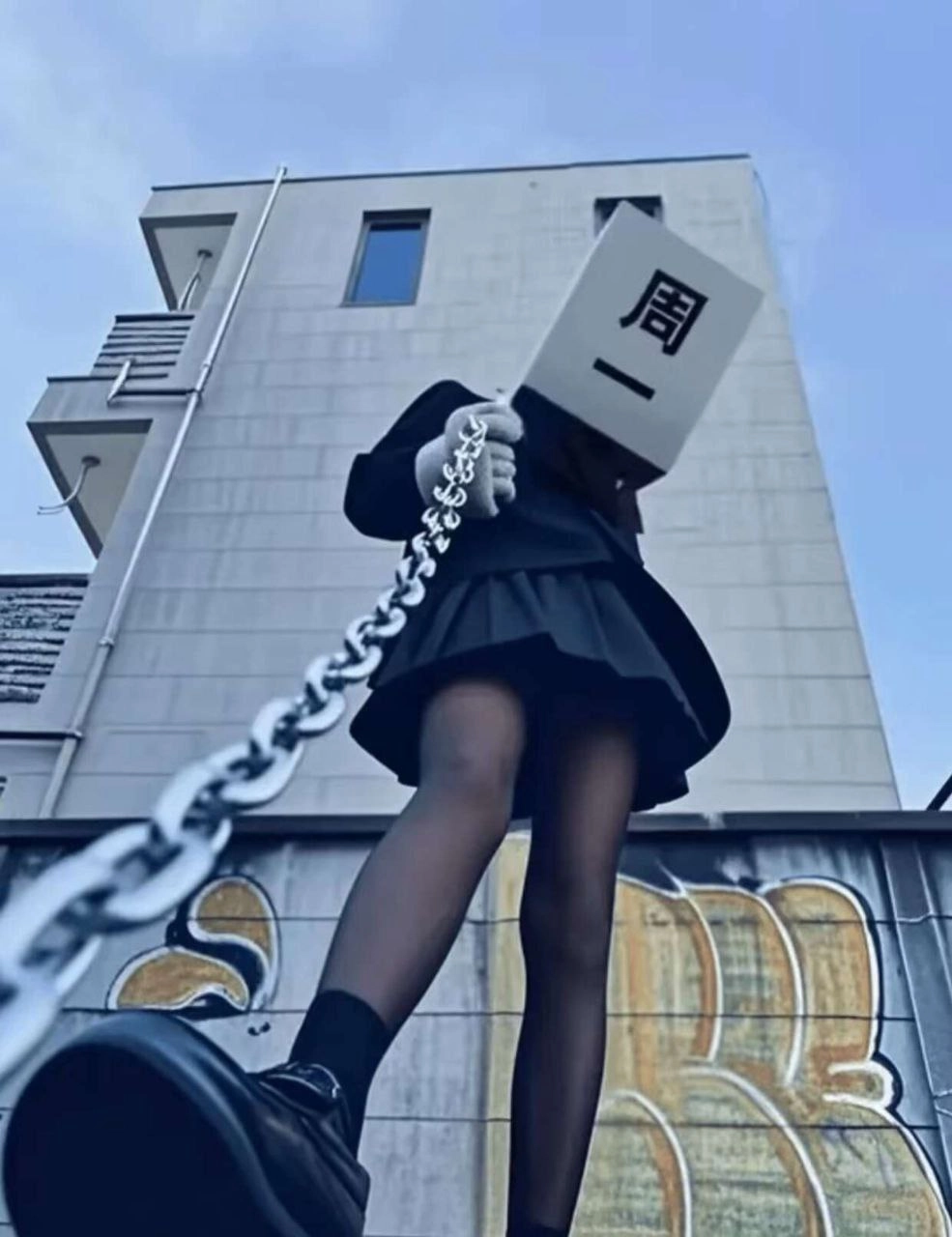 戴着白面具和黑色衣服的女人站在一个链子上。