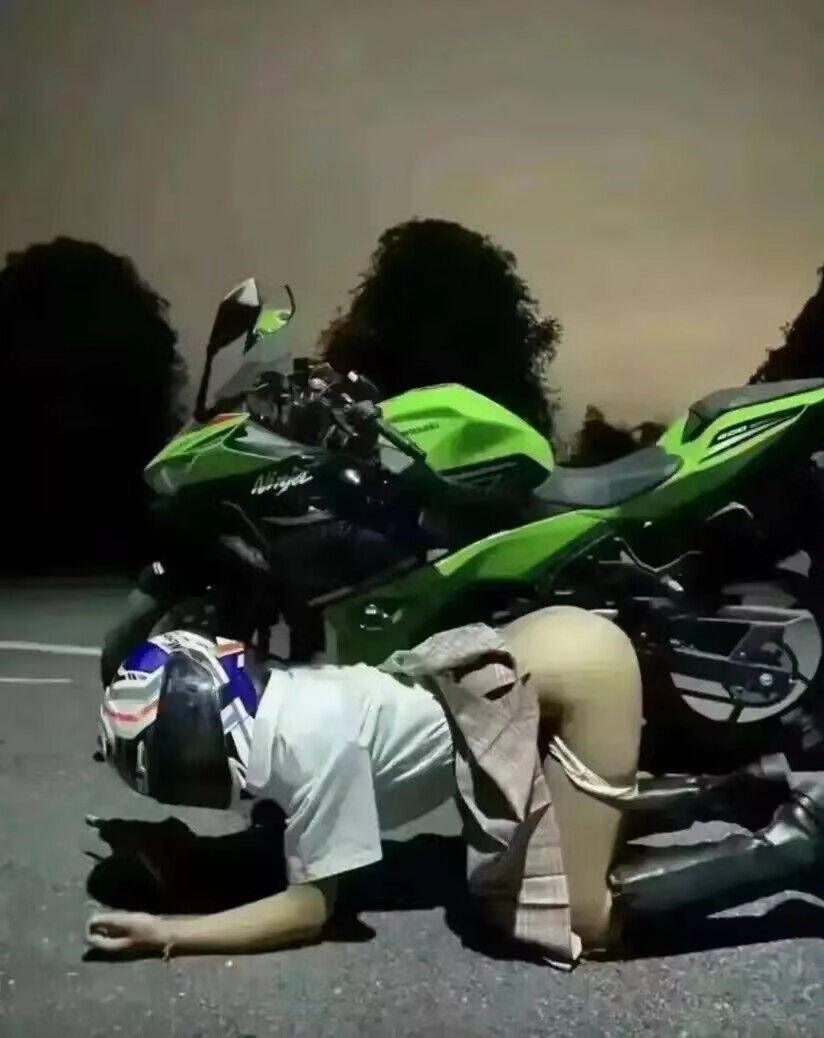 女人跪在摩托车前面。