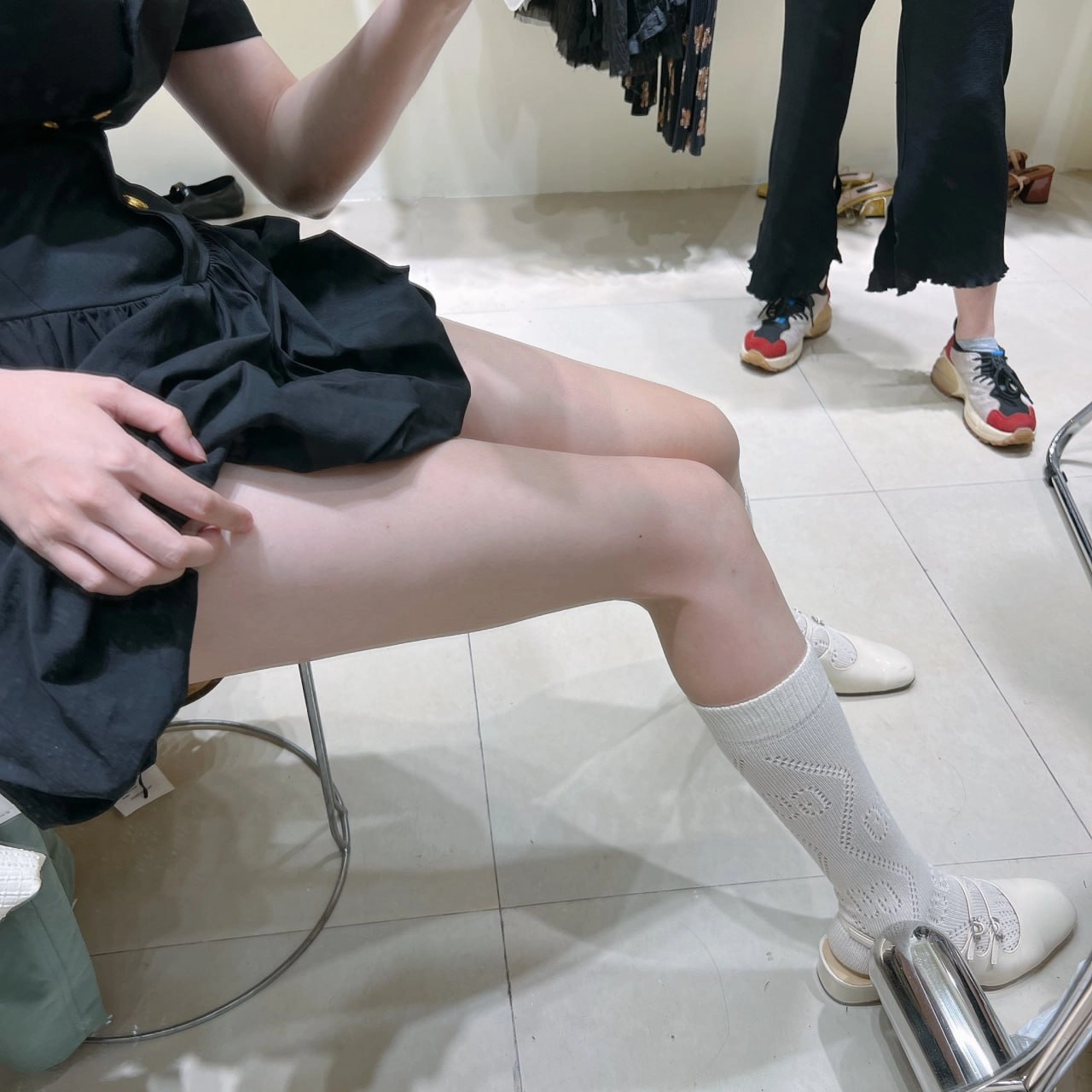 女人坐在椅子上,穿着白色袜子和黑色裙子。