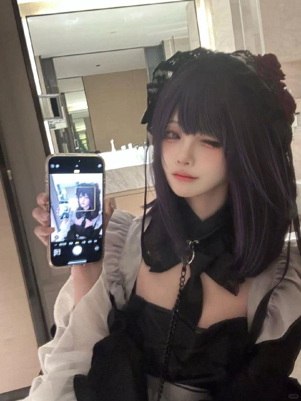 一位穿着黑色衣服的女人拿起手机拍照自己。