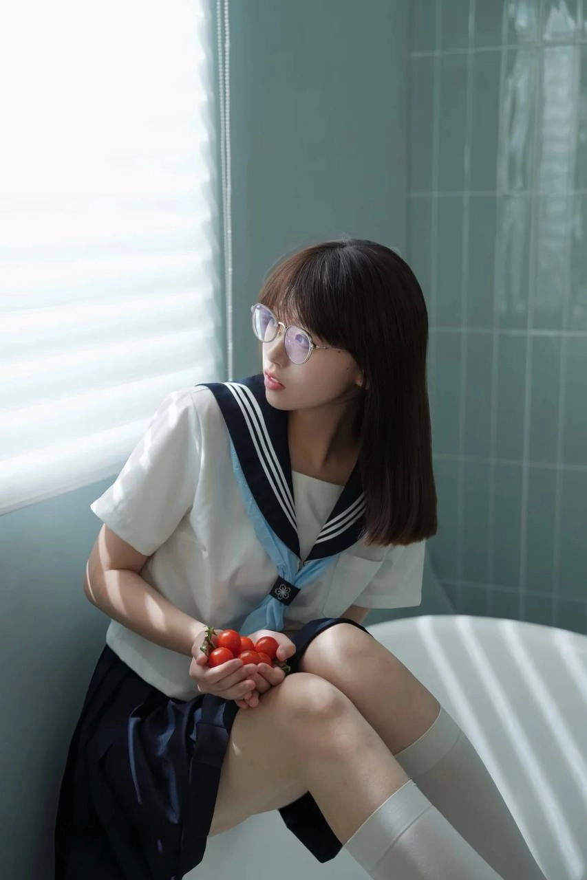 戴着眼镜和蓝色和白色的衬衫的女人坐在浴缸里。