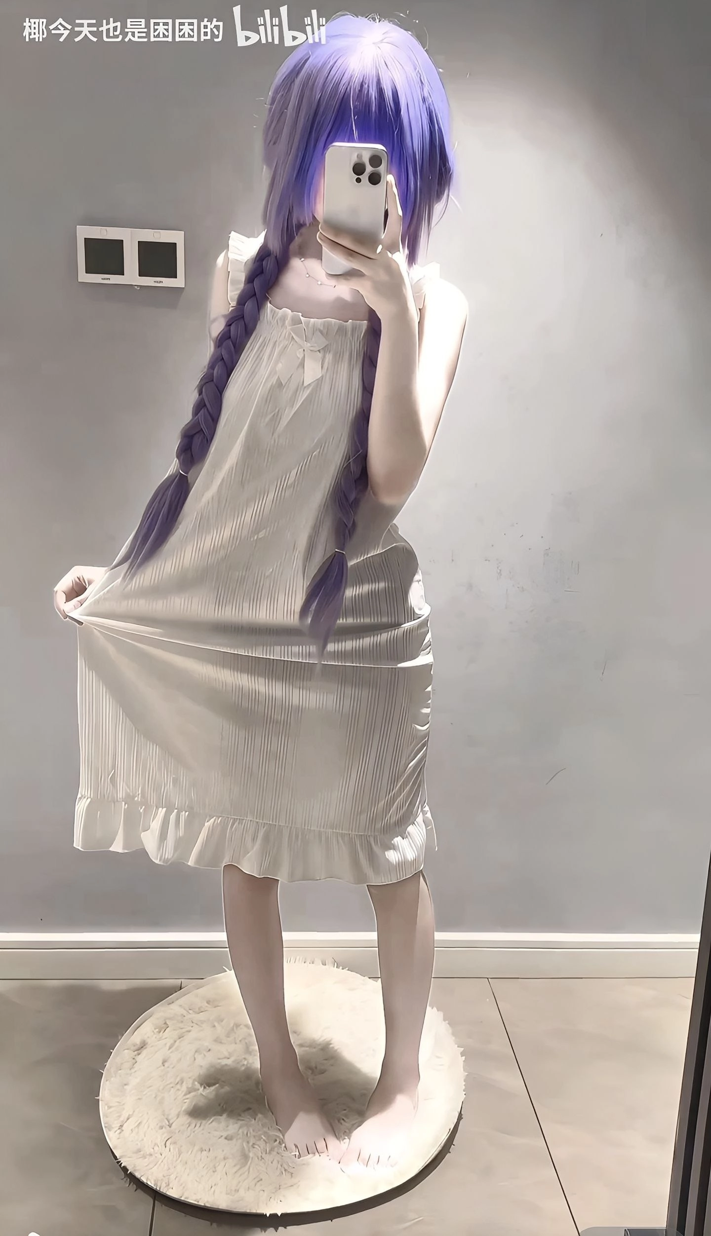 一位穿着紫色头发的白色裙子的女人拍了一张自拍。