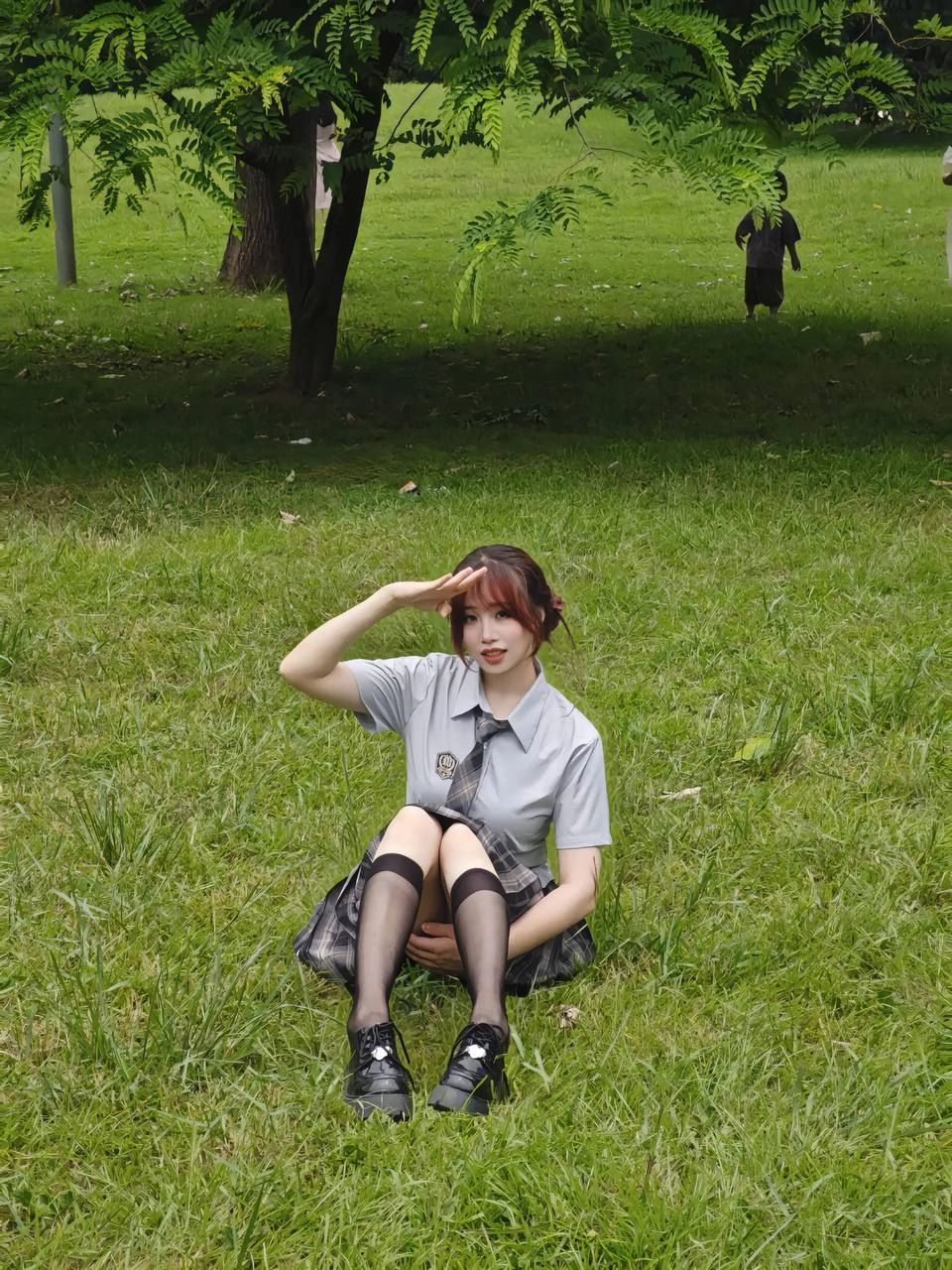 穿着灰色衬衫和黑色领带的女人坐在草地上。