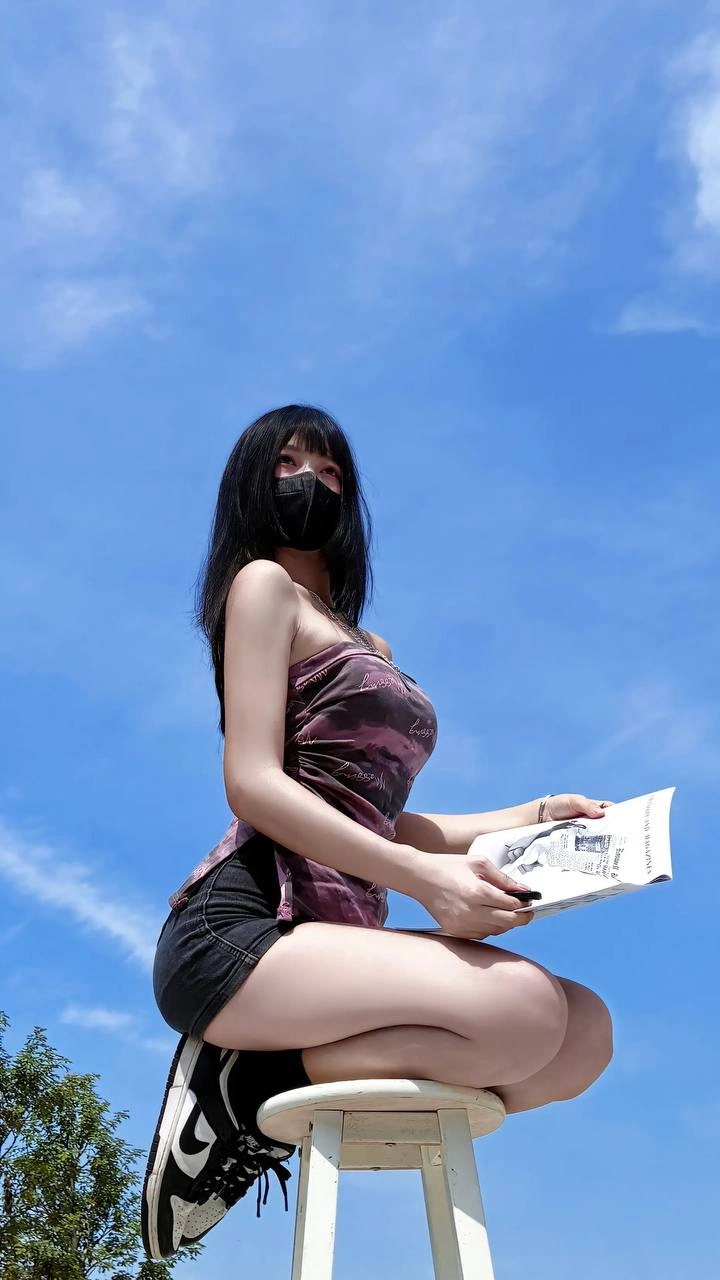 女人戴着面具,拿着一本书。