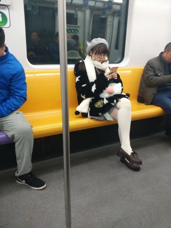 一位穿着黑色和白色外套的女人坐在地铁上。