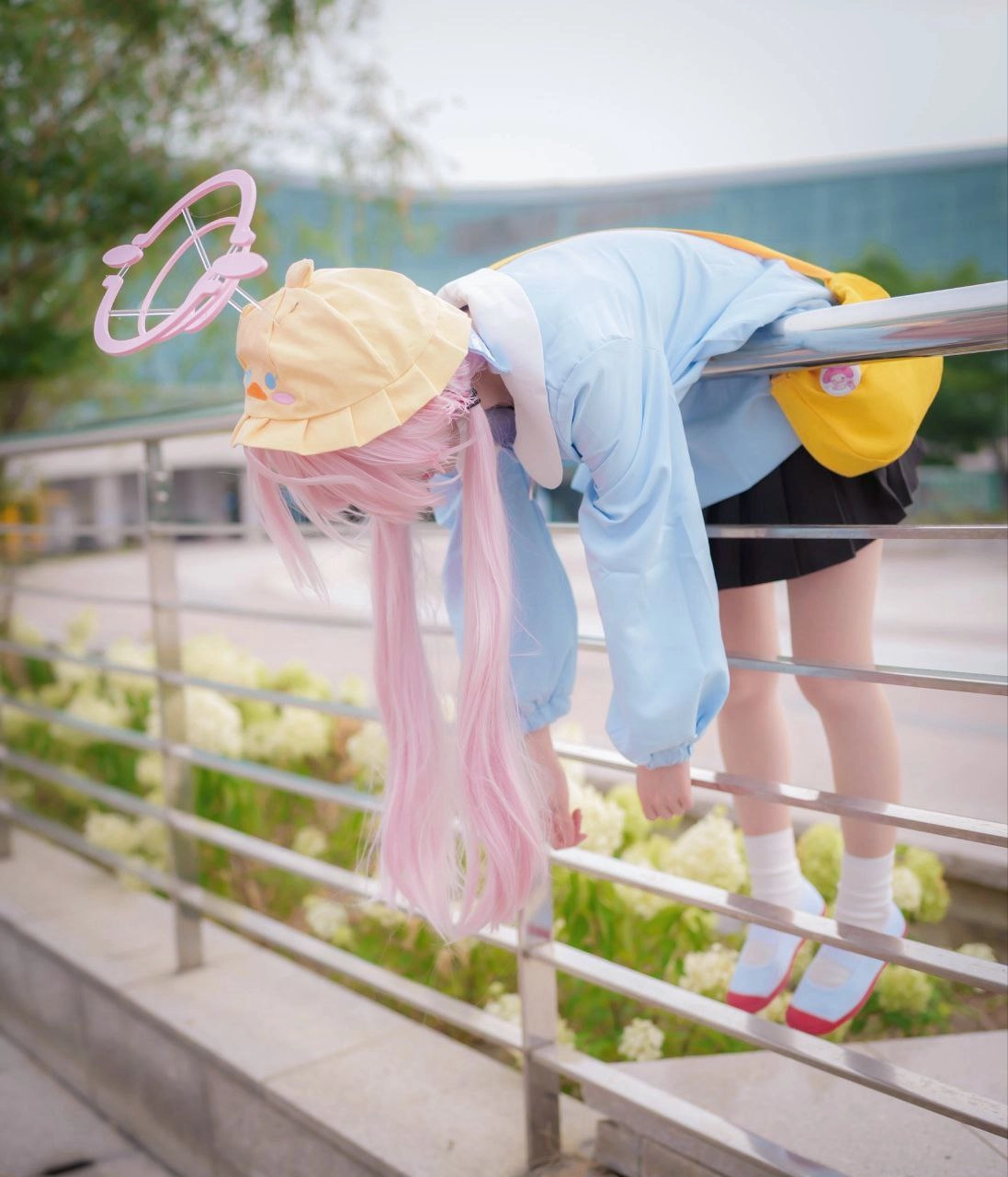 有粉红色的头发和一个黄色的帽子的女孩挂着她的头在一根子上。