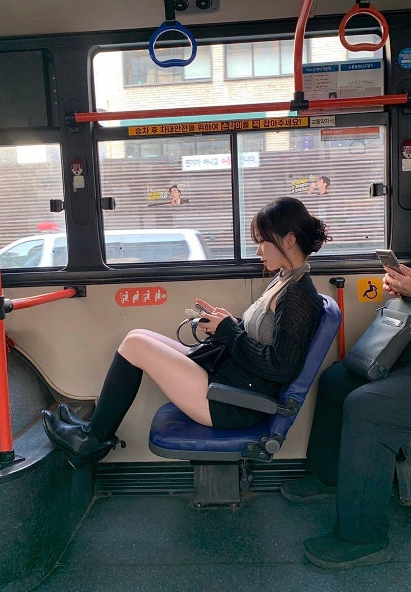 女人坐在公交车上,看着她的手机。