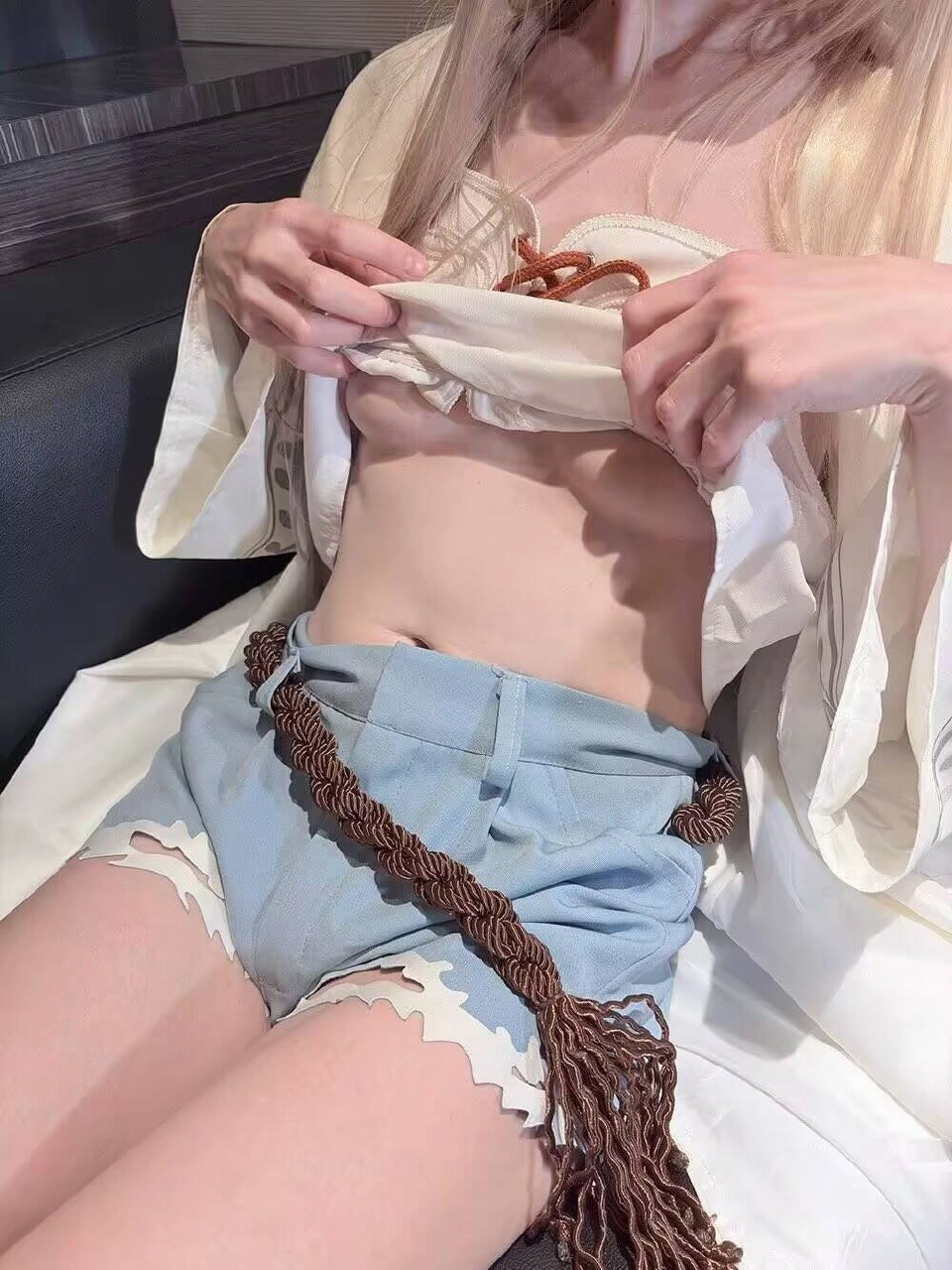 一位穿着白色衬衫和蓝色短裤的女人把衬衫敞开,揭示她的乳房。