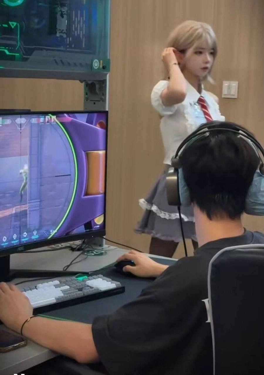 一位穿着红色弓和白色衬衫的女孩站在男人面前玩视频游戏。