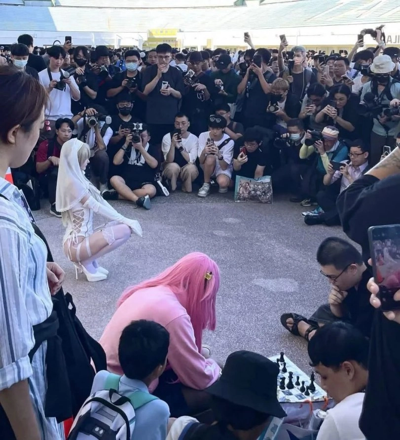 穿着白色衣服的女人跪在地上,站在一个象棋板前。