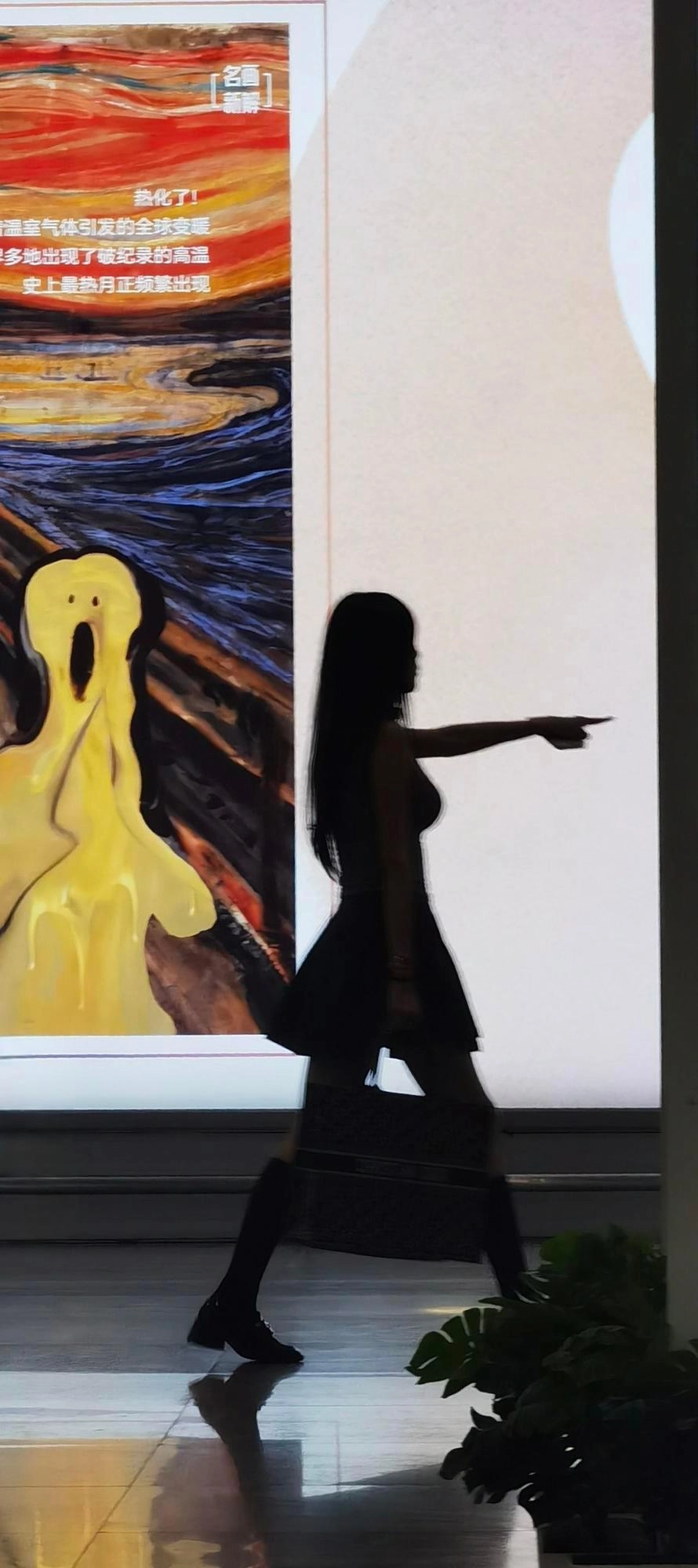 女人指着一幅尖叫的脸的画。