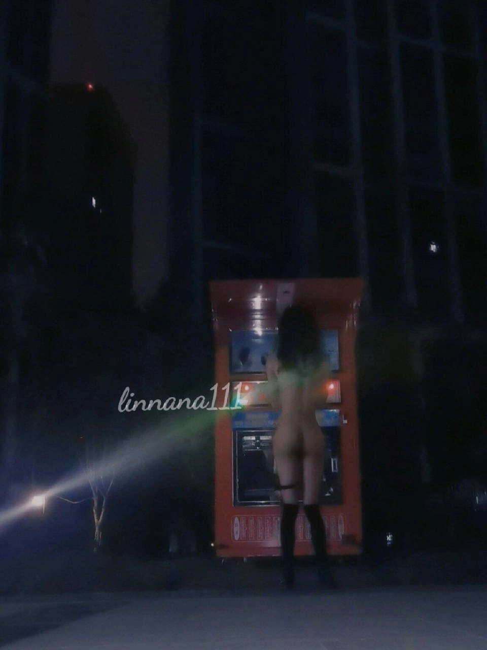 一位穿着白色衬衫的女人把钱放进了一台售货机。