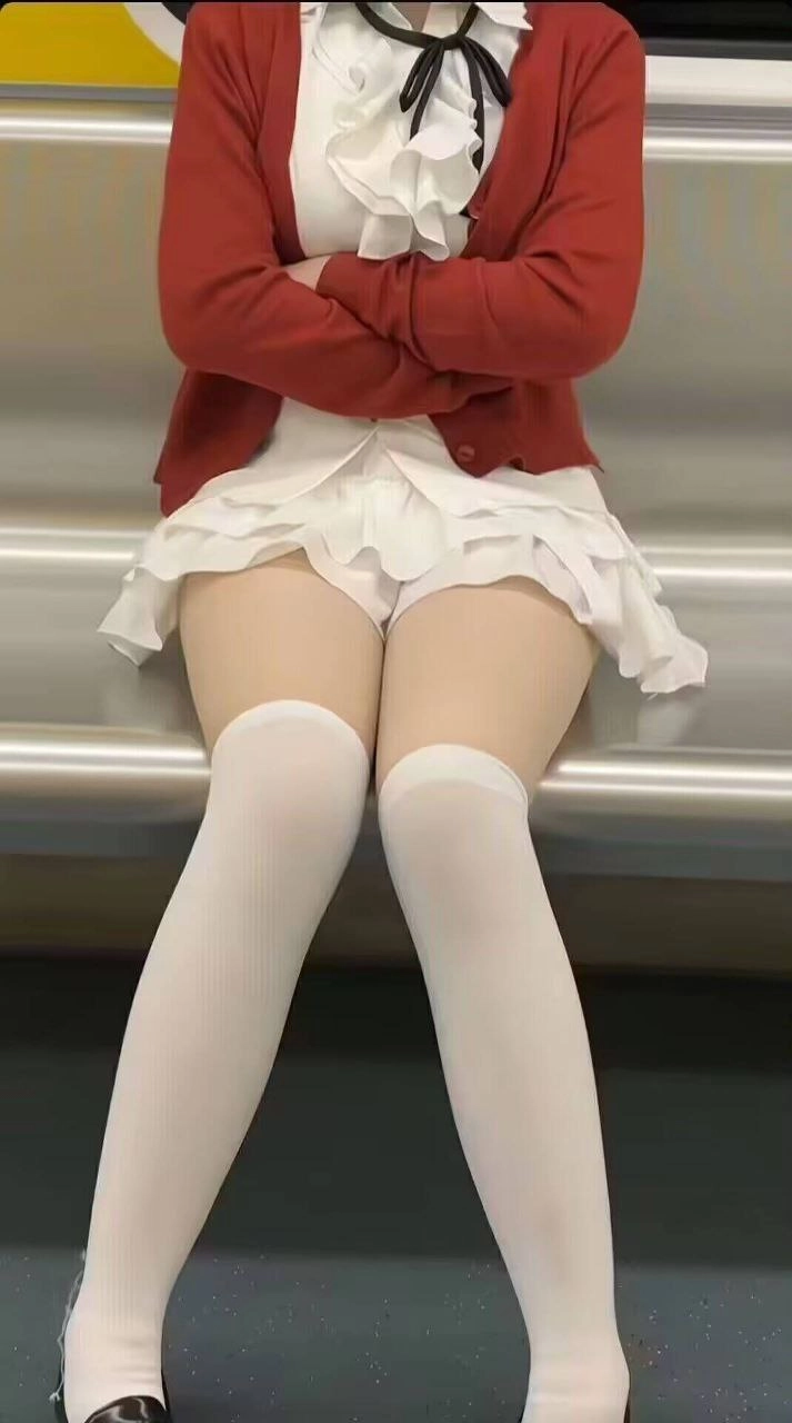 穿着红色夹克和白色裙子的女人坐在一个凳子上。