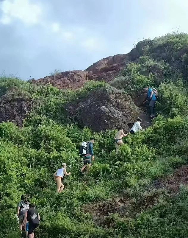 一群人爬上一座陡峭的山丘。