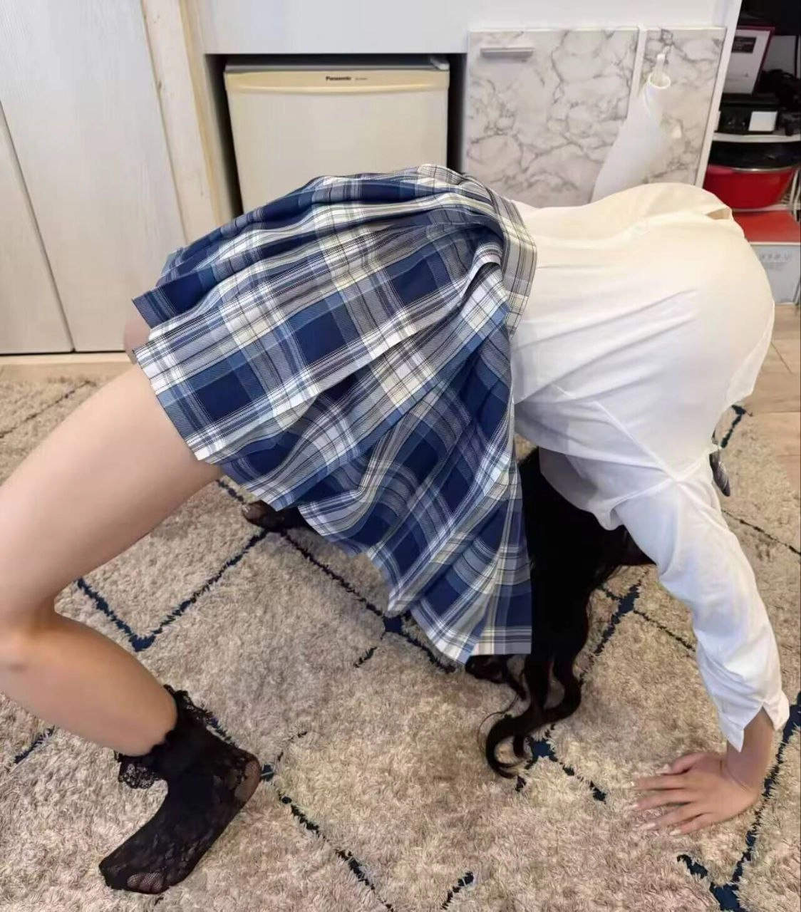 穿着蓝色和白色的裙的女孩在地毯上做手掌。