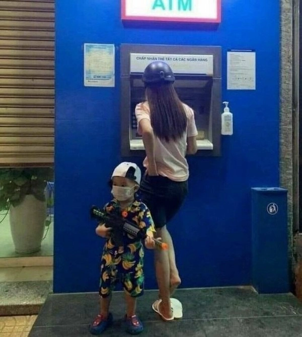 一名妇女和孩子站在ATM银行前面。