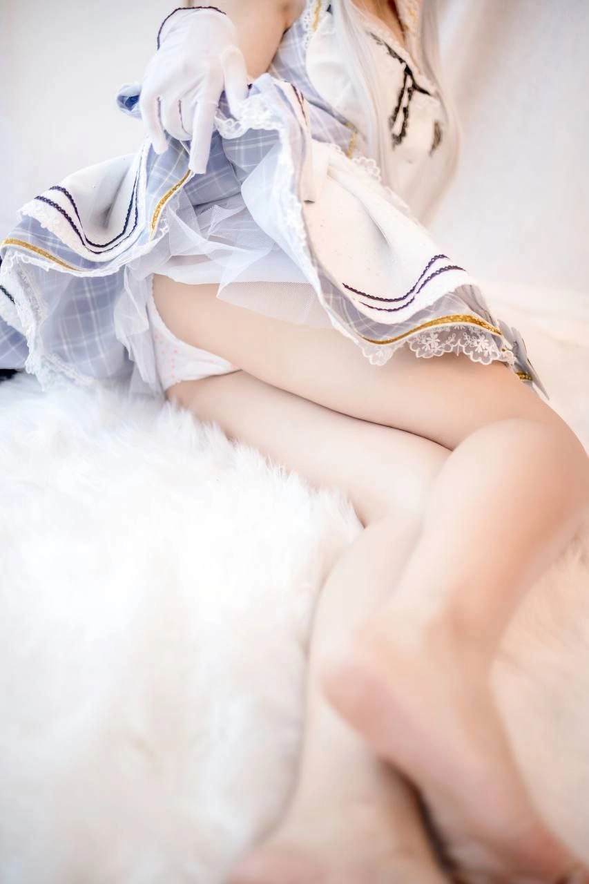 穿着白色裙子的女孩躺在一个白色的毯子上。