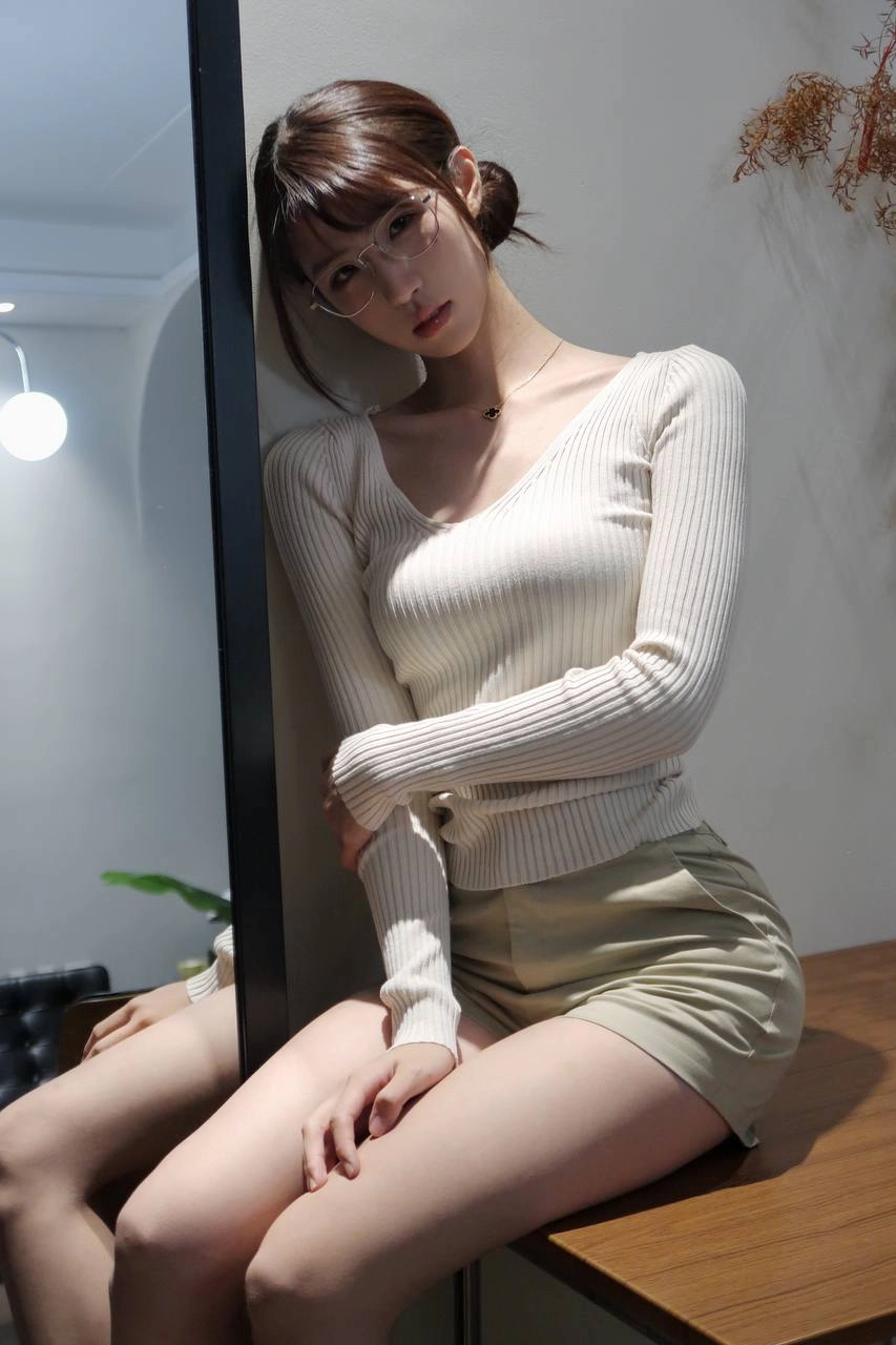 一位戴着眼镜和一件白色衬衫的女人倾斜在墙上。