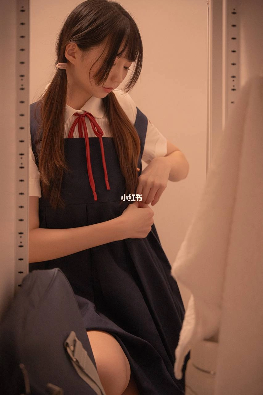 一位穿着白色衬衫和黑色裙子的女人坐在床上,拿着一罐苏打水。