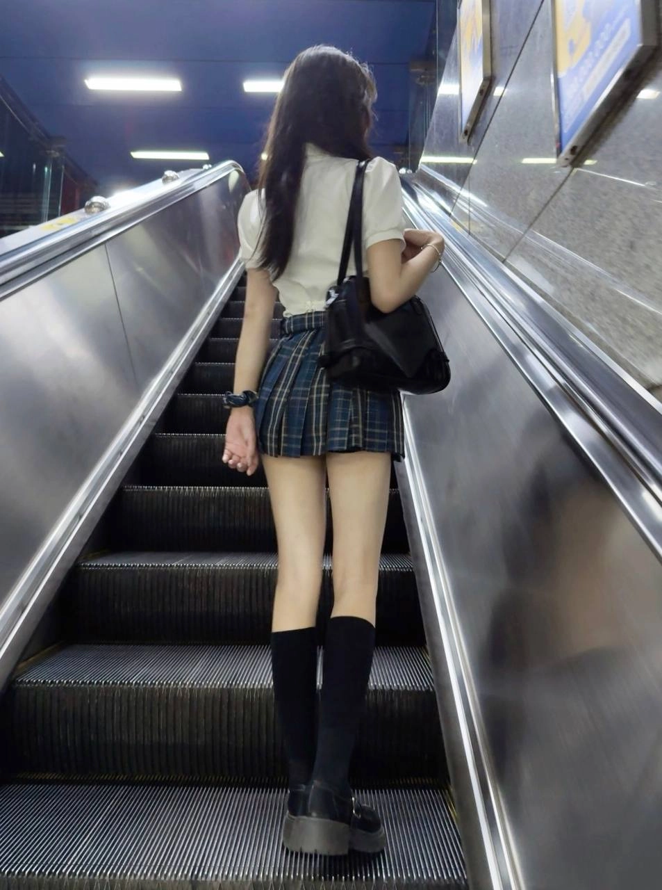 一位穿着裙子和黑靴的女人正在走下楼梯。