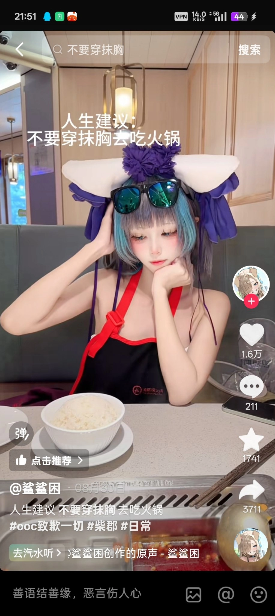 一位穿着黑色和红色的女人坐在一张桌子上,她面前有一碗食物。