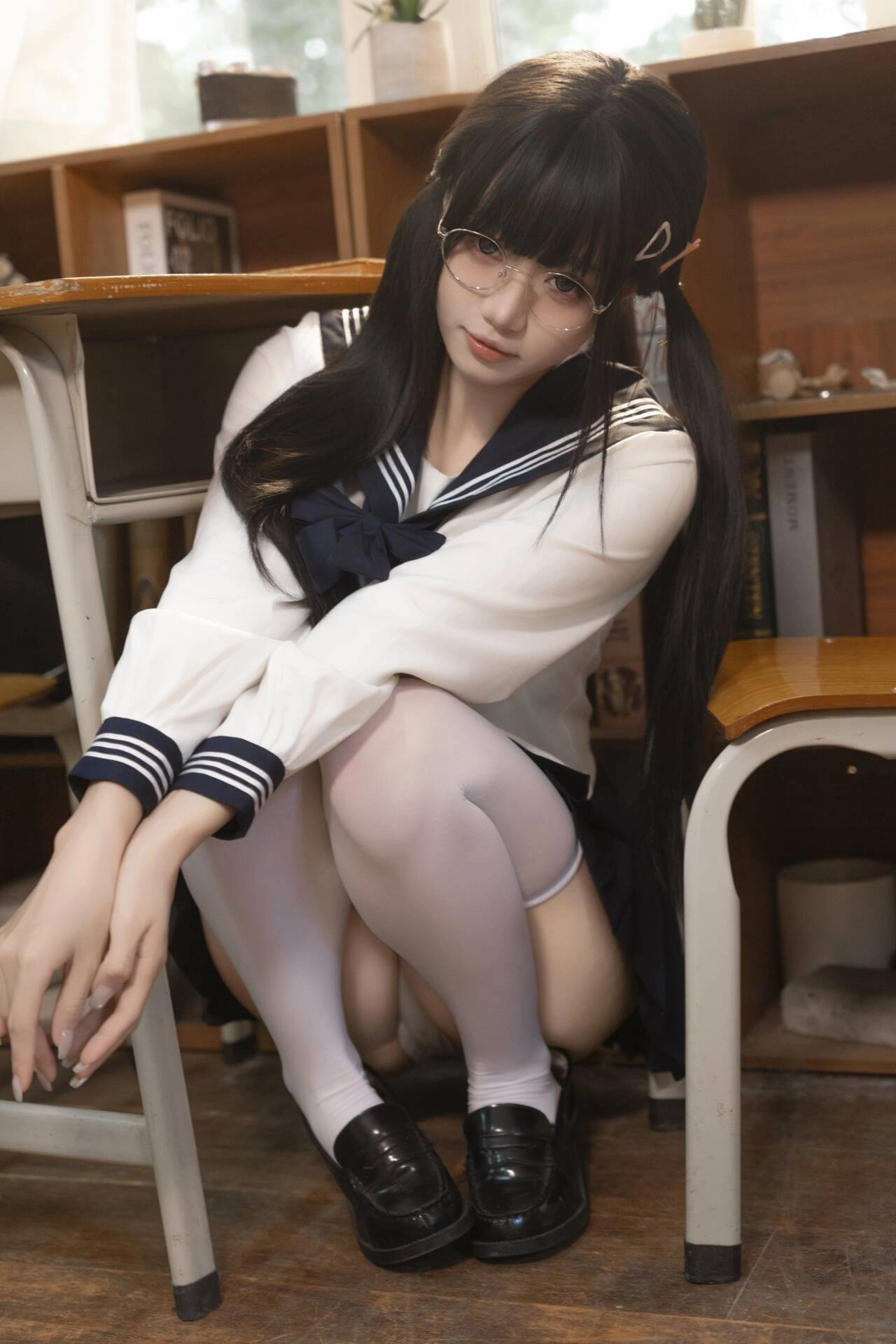 穿着白色和蓝色裙子的女孩坐在椅子上。