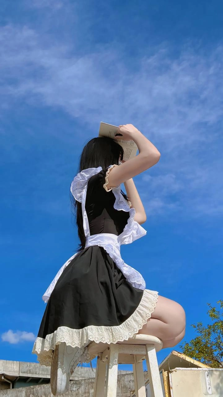 戴着面具和女仆服装的女人站在天空中。