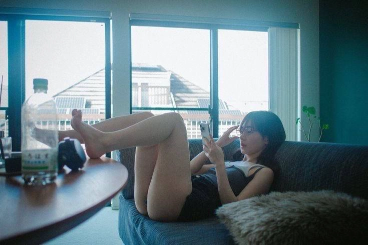 女人坐在沙发上,看着她的手机。