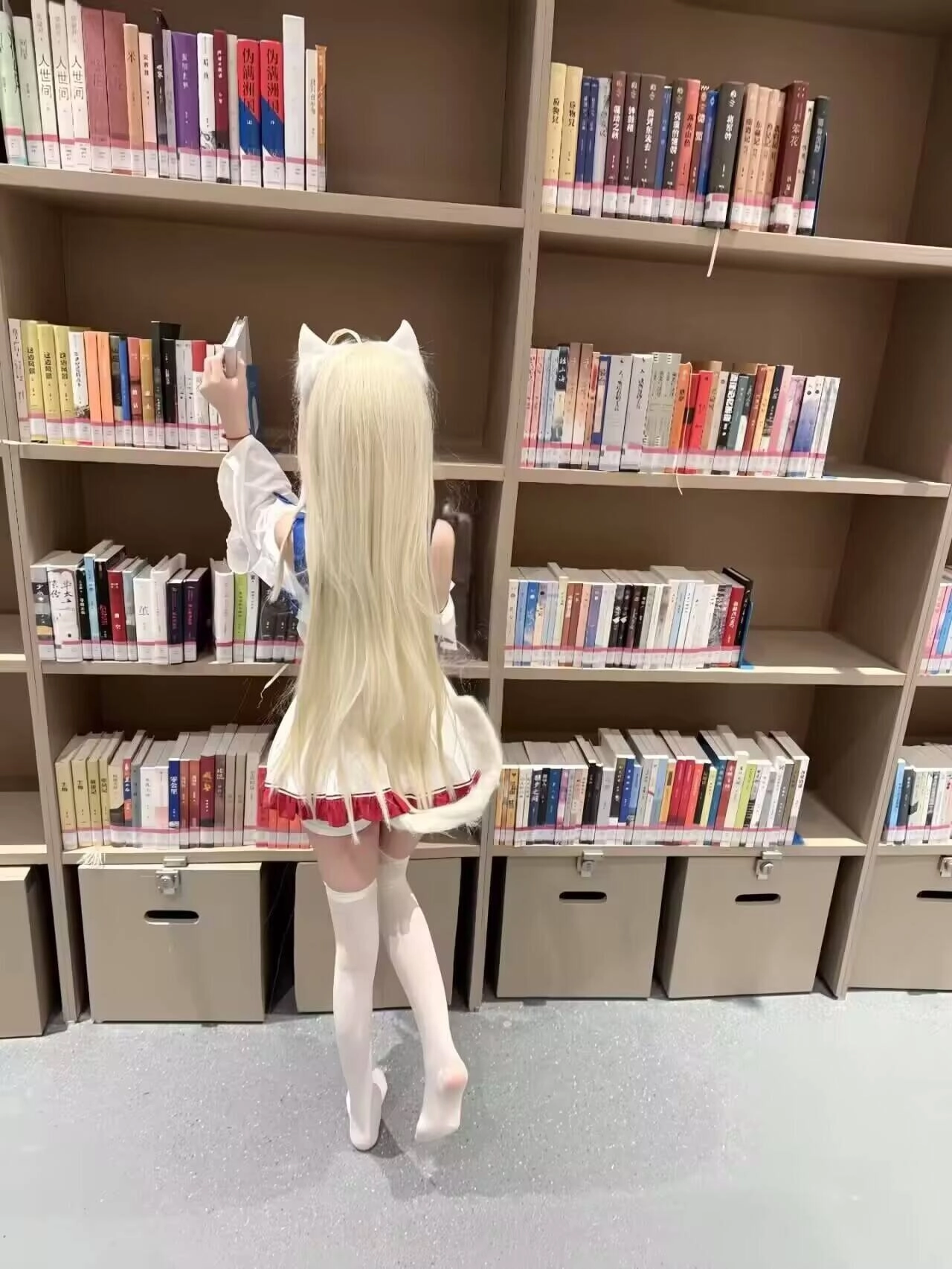 长发和白色裙子的女孩站在书架前面。