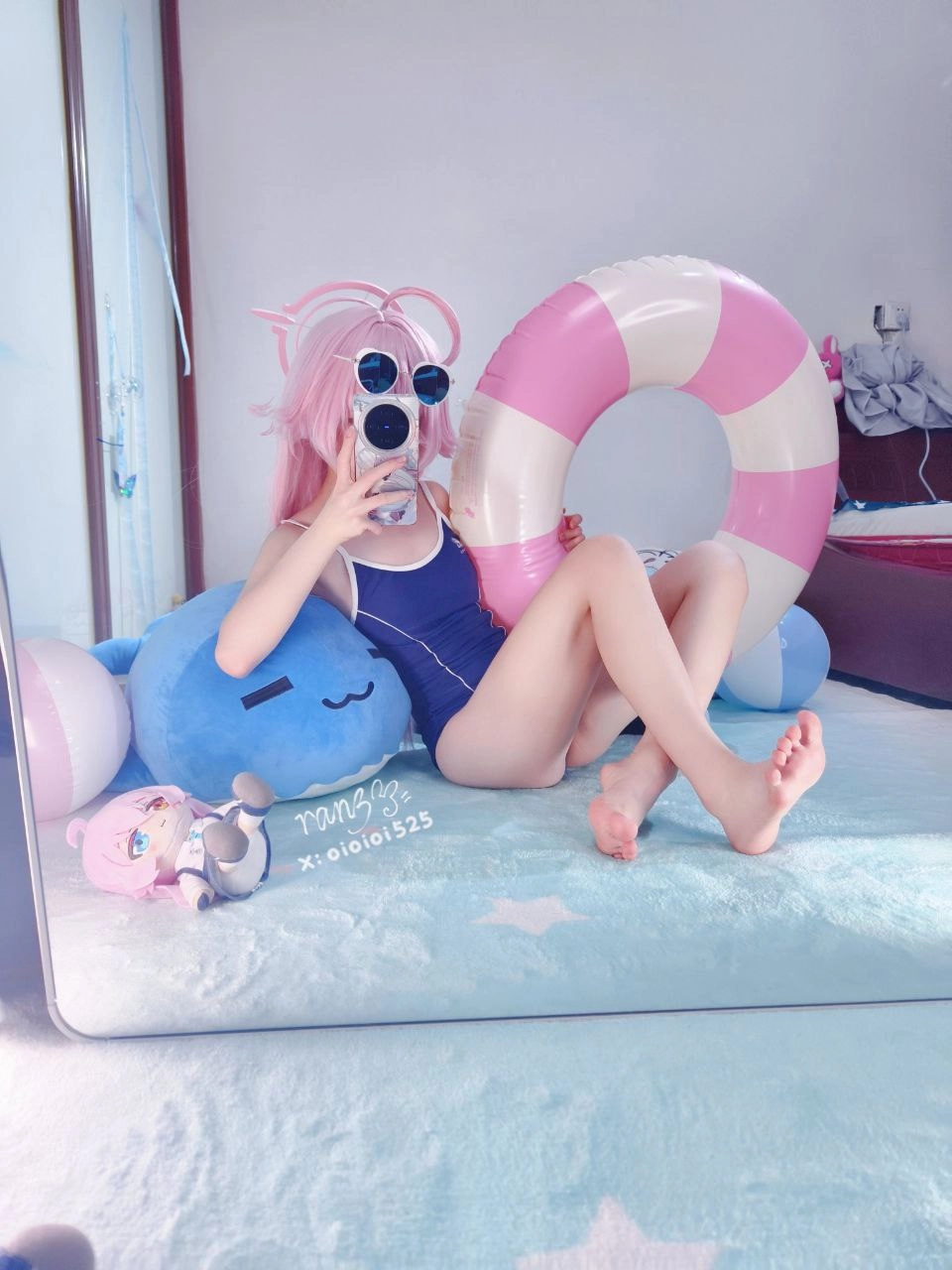 粉红色头发和蓝色泳衣的女孩在粉红色和蓝色的充气架前拍自拍。