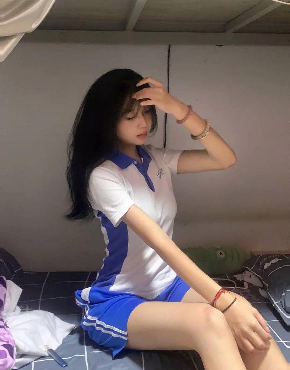 黑头发和蓝衬衫的女人坐在床上。