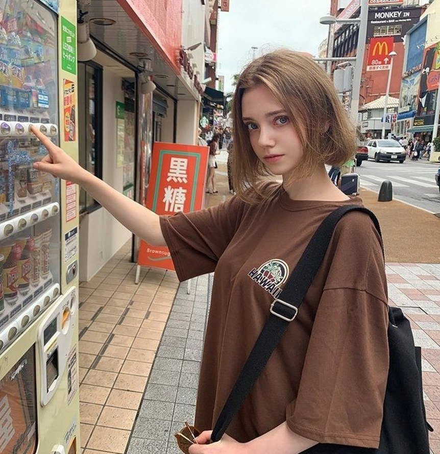 穿着棕色衬衫的女人拿着一台售货机。